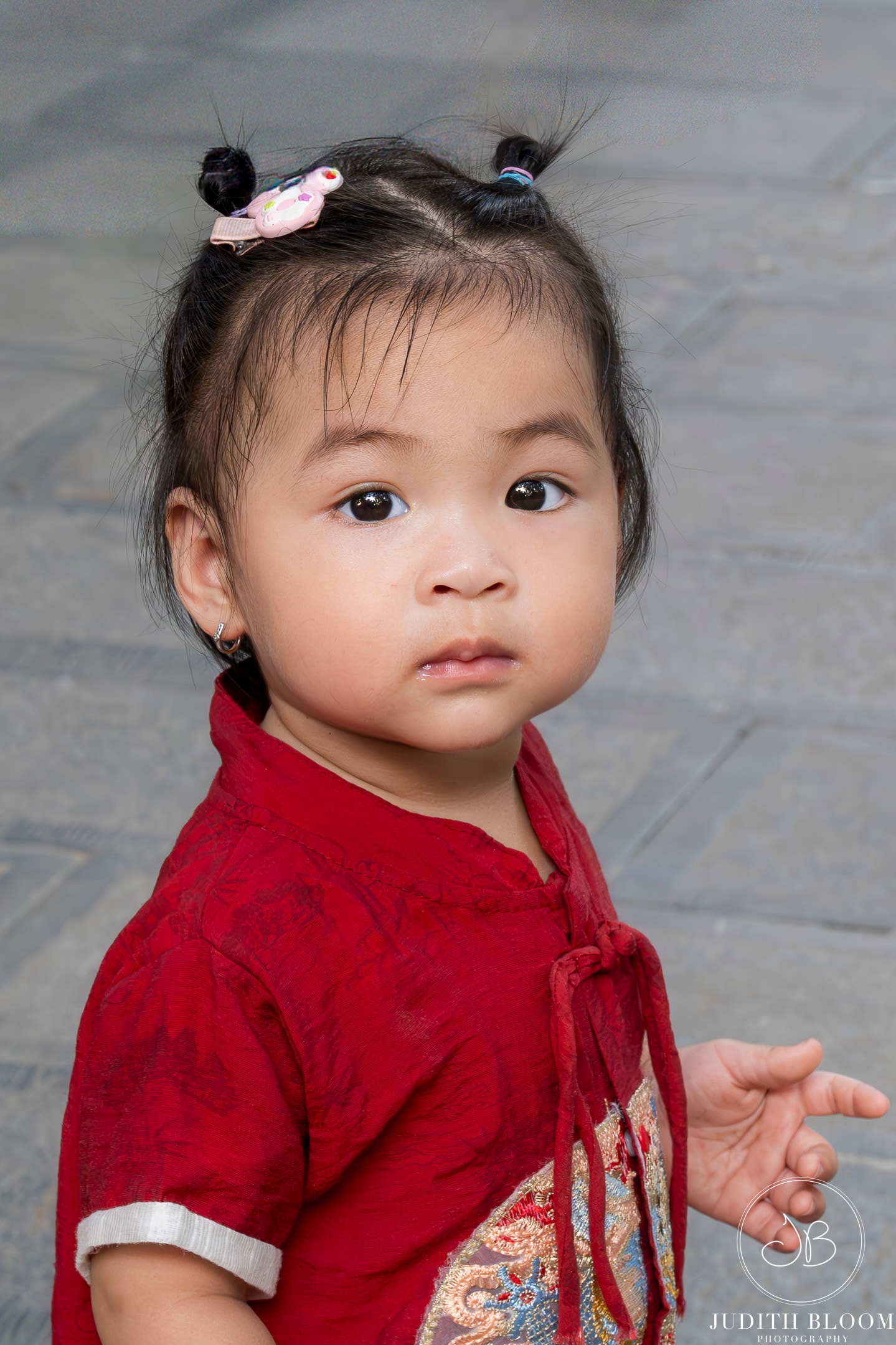 Portrait of a young child in a red embroidered traditional Vietnamese dress, Hanoi