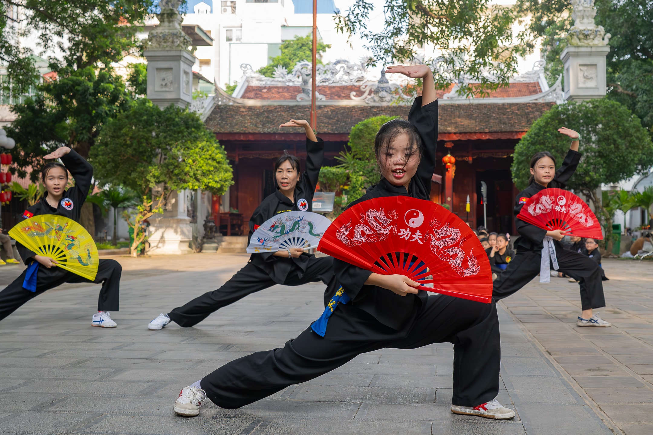 Young martial arts performers with decorative dragon fans at a Hanoi temple